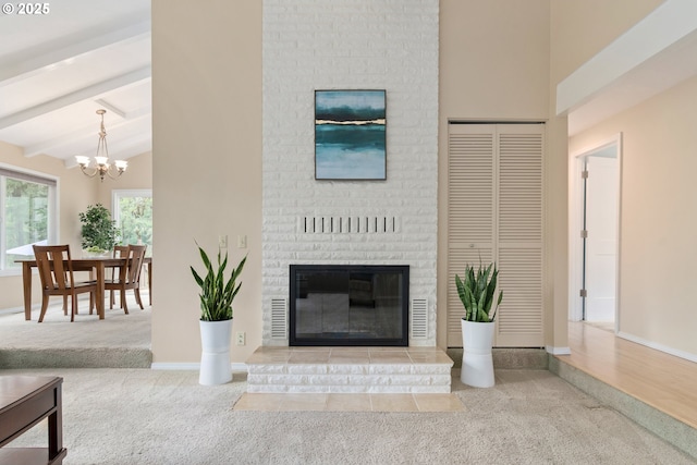 carpeted living room featuring baseboards, a chandelier, a fireplace, and beamed ceiling