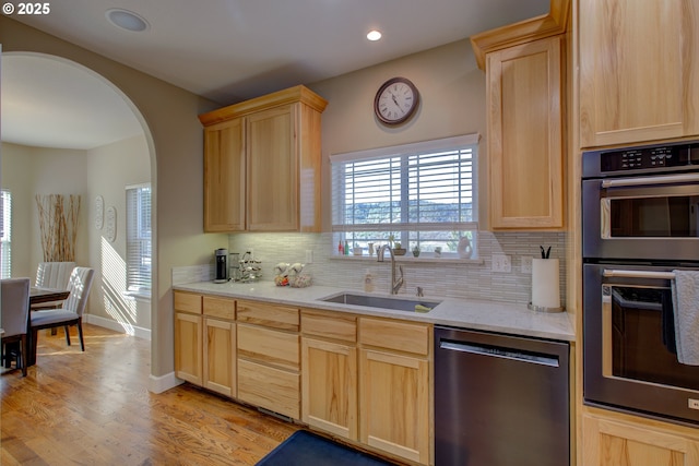 kitchen with tasteful backsplash, a notable chandelier, light brown cabinets, black refrigerator with ice dispenser, and light hardwood / wood-style flooring