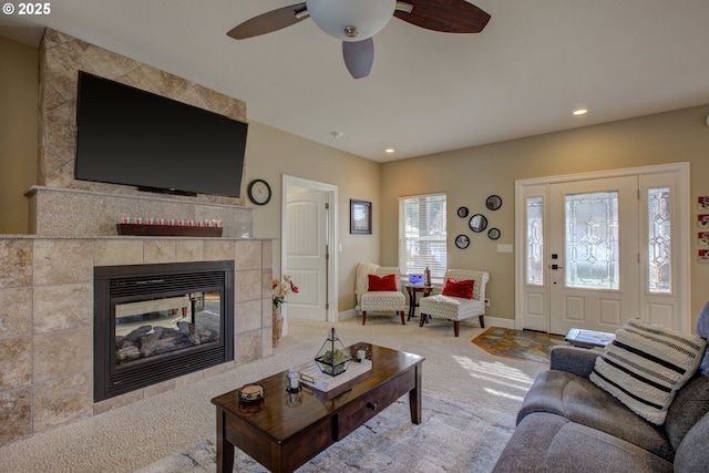 carpeted living room featuring ceiling fan and a tile fireplace