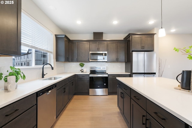 kitchen with pendant lighting, sink, appliances with stainless steel finishes, backsplash, and dark brown cabinetry