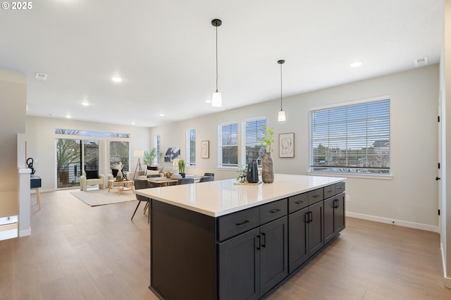 kitchen with decorative light fixtures, a center island, and light wood-type flooring