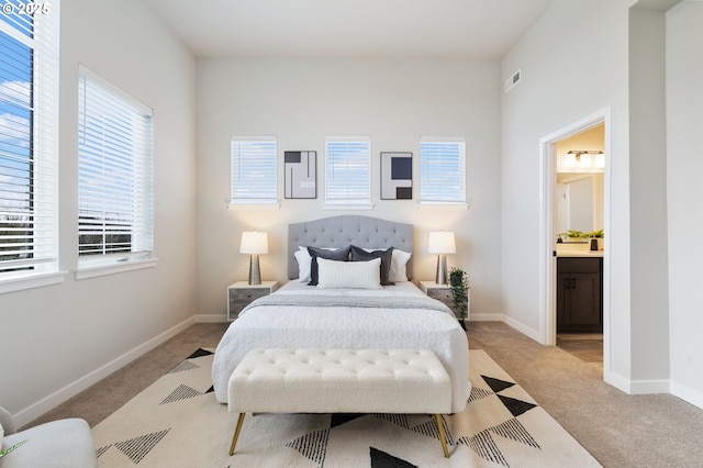 bedroom featuring light carpet and ensuite bath