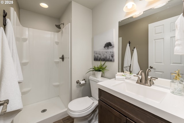 bathroom with toilet, a shower, and vanity