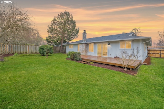 back house at dusk featuring a wooden deck and a lawn