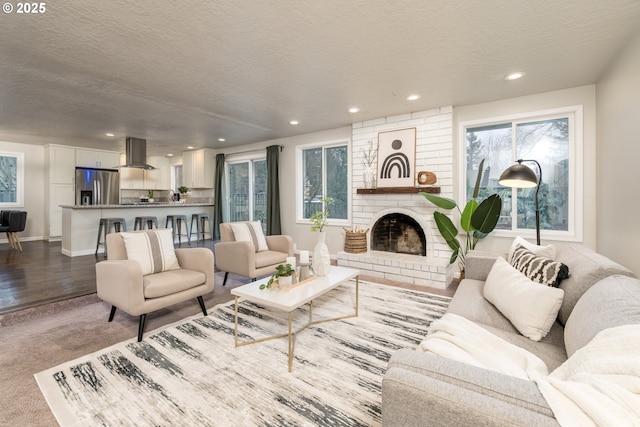 living room featuring light colored carpet, a brick fireplace, and a textured ceiling