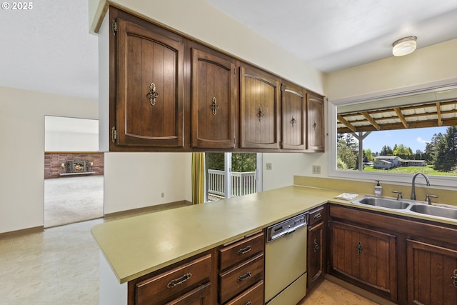 kitchen with dishwasher, a sink, a peninsula, light countertops, and light colored carpet