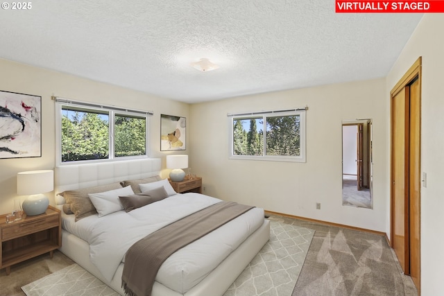 carpeted bedroom featuring a textured ceiling, a closet, and baseboards