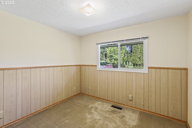 empty room featuring a textured ceiling, carpet flooring, and ornamental molding
