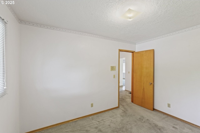 empty room featuring ornamental molding, a textured ceiling, and baseboards
