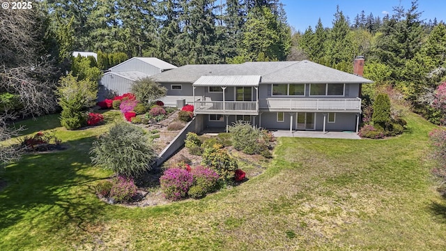 back of house featuring a patio area, a chimney, a lawn, and a deck