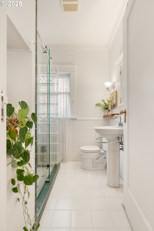 2083 NW Johnson St Unit 34, Portland, OR 97209 - bathroom featuring crown molding, a stall shower, toilet, tile patterned floors, and tile walls