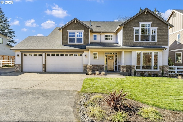 craftsman-style house with driveway, stone siding, a front yard, and fence