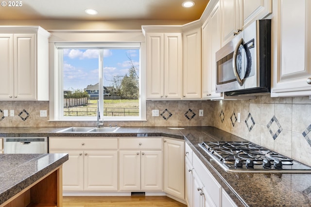 kitchen featuring decorative backsplash, tile countertops, light wood-style flooring, stainless steel appliances, and a sink