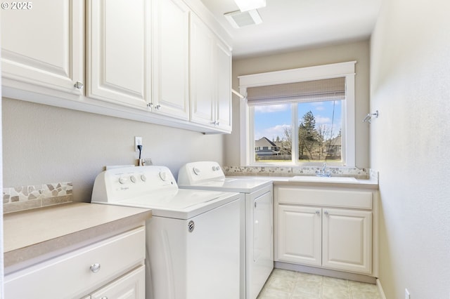 clothes washing area with a sink, visible vents, washing machine and dryer, and cabinet space