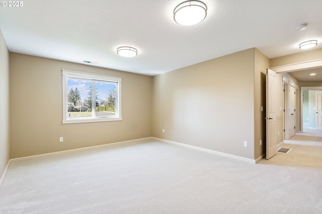 empty room featuring baseboards, visible vents, and light colored carpet