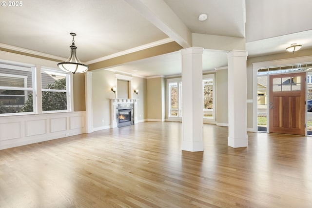 foyer featuring plenty of natural light, decorative columns, and light wood-style flooring