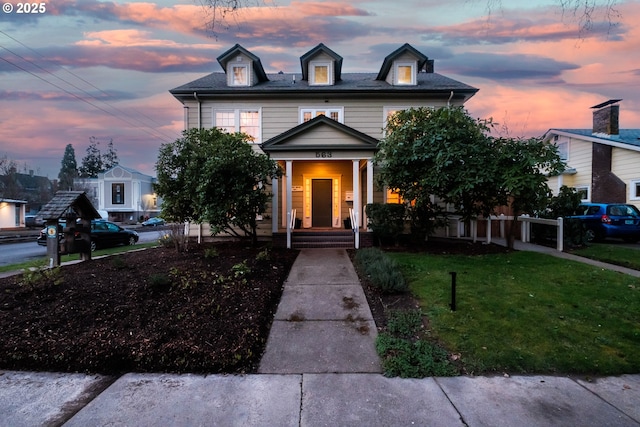 american foursquare style home featuring covered porch and a front lawn