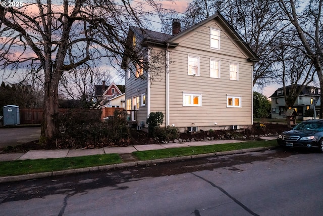 view of side of home featuring a chimney and fence