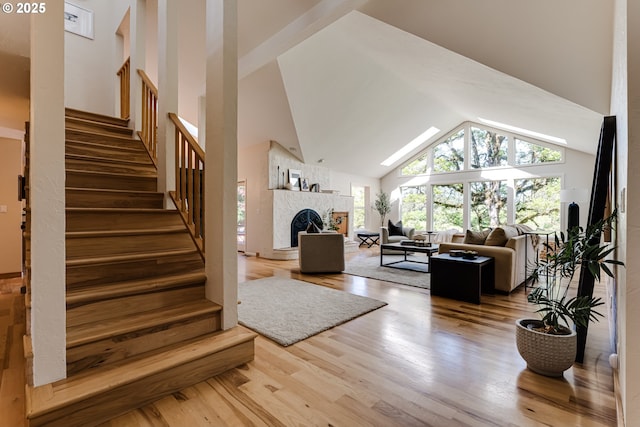 interior space with high vaulted ceiling, wood finished floors, and a fireplace