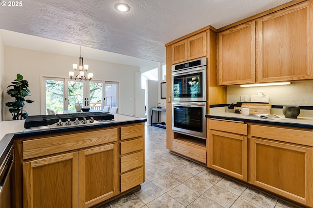 kitchen featuring an inviting chandelier, light tile patterned flooring, double oven, gas cooktop, and a textured ceiling