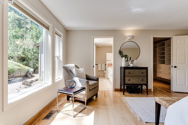 living area featuring baseboards, visible vents, a healthy amount of sunlight, and light wood finished floors