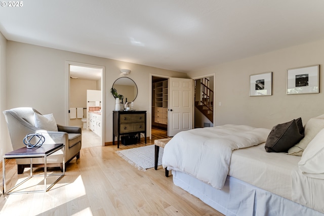 bedroom featuring light wood-type flooring, ensuite bathroom, and a walk in closet