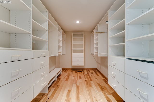 walk in closet with light wood finished floors