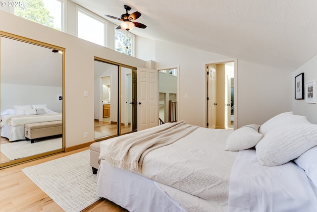 bedroom with a ceiling fan, high vaulted ceiling, wood finished floors, and ensuite bathroom