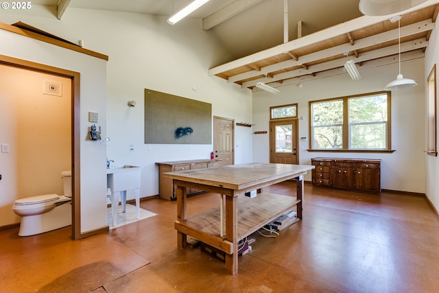 dining room with beamed ceiling, baseboards, finished concrete floors, and high vaulted ceiling