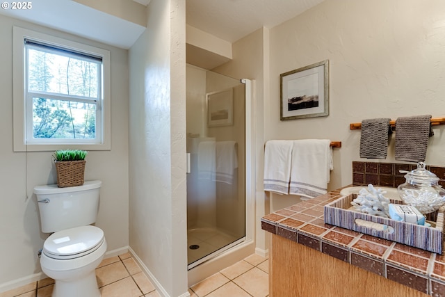 bathroom with toilet, baseboards, tile patterned flooring, and a stall shower