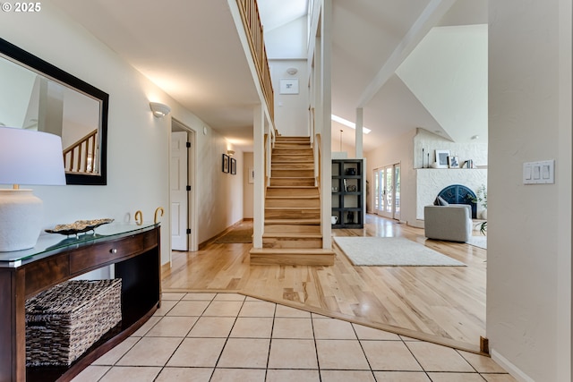 entrance foyer featuring baseboards, light tile patterned floors, vaulted ceiling, and stairway