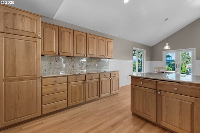 89523 Manion Dr, Warrenton, OR 97146 - kitchen featuring light wood-style floors, french doors, a wainscoted wall, vaulted ceiling, and light stone countertops