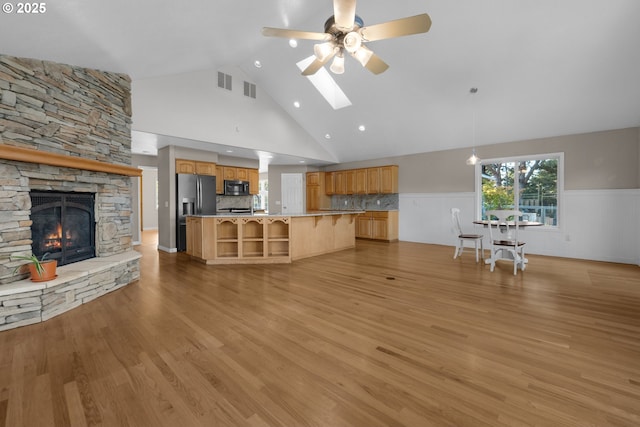 89523 Manion Dr, Warrenton, OR 97146 - unfurnished living room with a wainscoted wall, ceiling fan, high vaulted ceiling, a stone fireplace, and light wood-style flooring