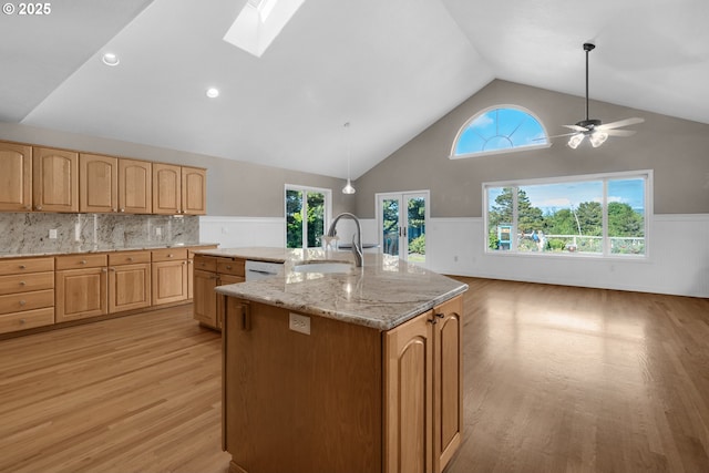 89523 Manion Dr, Warrenton, OR 97146 - kitchen featuring light wood finished floors, wainscoting, healthy amount of natural light, a kitchen island with sink, and a skylight