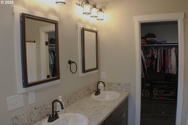 bathroom with double vanity, a sink, and a spacious closet