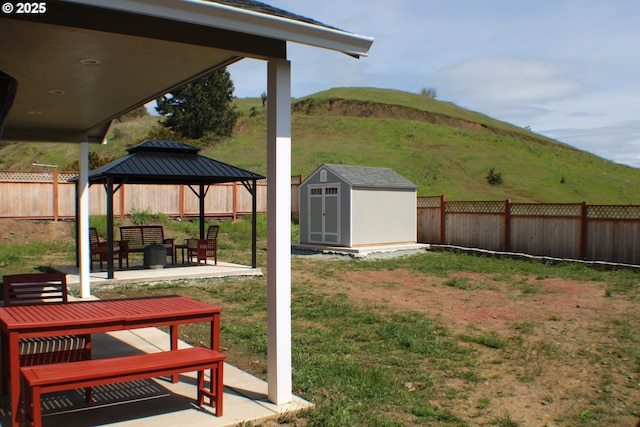 view of yard with a storage shed, a fenced backyard, an outdoor structure, a patio area, and a gazebo