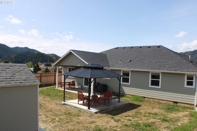 rear view of house with fence, a patio, a gazebo, and a mountain view