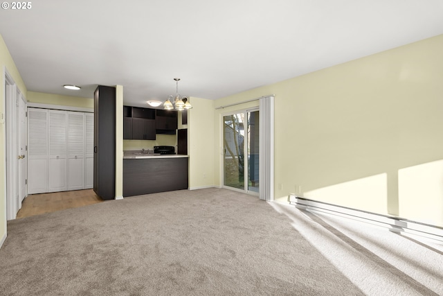 unfurnished living room featuring an inviting chandelier, baseboard heating, and light carpet