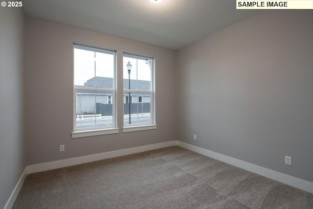 carpeted spare room with a textured ceiling and baseboards