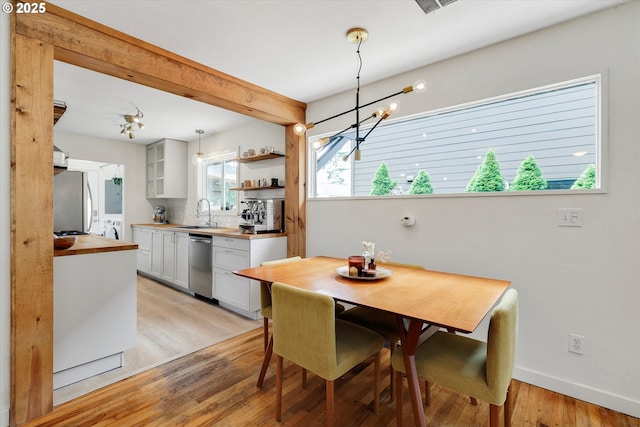 9014 N John Ave, Portland, OR 97203 - dining area with washing machine and dryer, a chandelier, light wood-style flooring, and baseboards