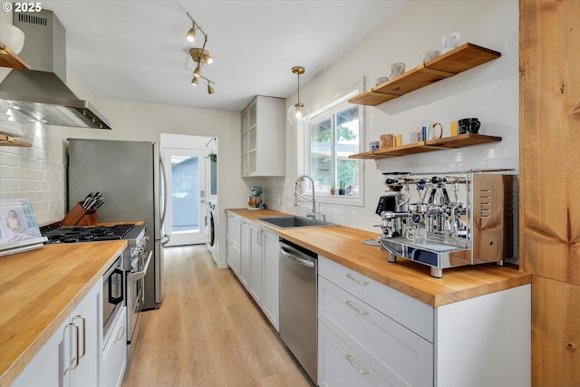 9014 N John Ave, Portland, OR 97203 - kitchen with butcher block counters, appliances with stainless steel finishes, a sink, and wall chimney exhaust hood