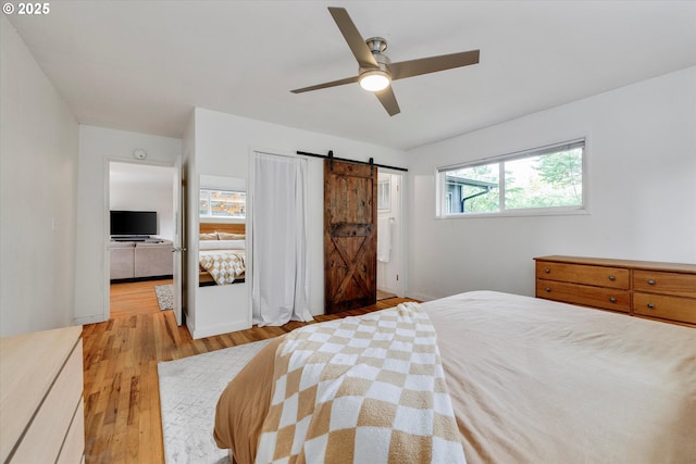 9014 N John Ave, Portland, OR 97203 - bedroom with a barn door, light wood-style flooring, and a ceiling fan