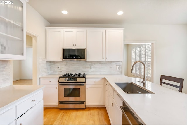2435 NW Burnett St, Portland, OR 97229 - kitchen featuring stainless steel appliances, backsplash, light countertops, white cabinets, and recessed lighting