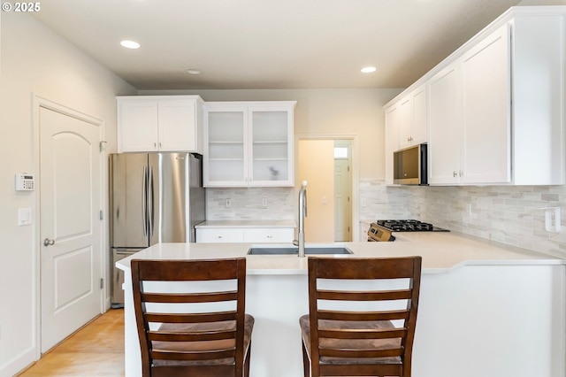 2435 NW Burnett St, Portland, OR 97229 - kitchen with stainless steel appliances, glass insert cabinets, light countertops, a peninsula, and tasteful backsplash