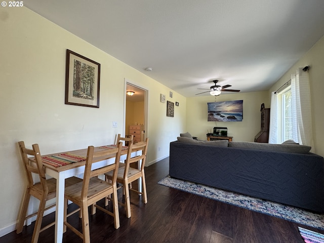 dining space with baseboards, a ceiling fan, and dark wood-type flooring