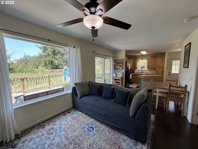 living area featuring baseboards, ceiling fan, and wood finished floors