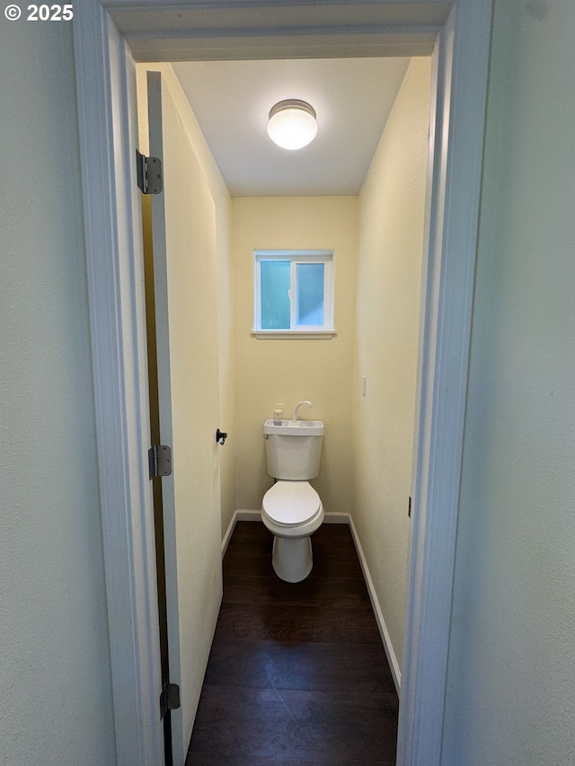 bathroom with toilet, baseboards, and wood finished floors