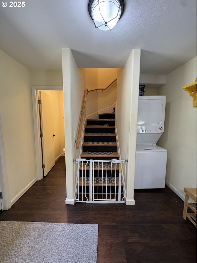stairway featuring baseboards, stacked washer / drying machine, and wood finished floors