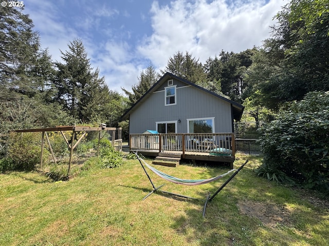 rear view of property with a lawn, a deck, and fence
