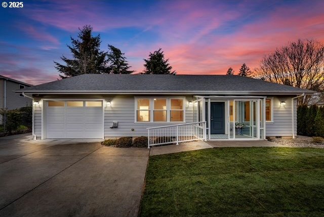 single story home featuring a garage, covered porch, and a lawn